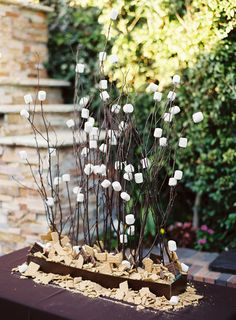 a table topped with lots of white flowers and rocks on top of each other next to a brick wall