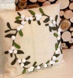 a decorative pillow made out of white cotton and green leaves is sitting on a table