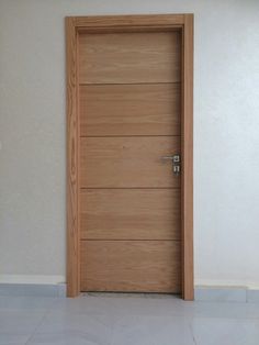 an empty room with a wooden door and tile flooring in front of the wall