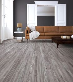 a living room with wood flooring and gray walls, white trimming on the couch