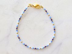 Simple beaded bracelet for women. Made with Miyuki Delica beads in different shades of blue and highlighted with gold beads. Perfect for everyday use and for stacking with other bracelets. Perfect gift for women. The chain and clasp are 24k gold plated brass. Each jewelry item comes in a colorful envelope, as seen in the last picture, and is ready to be gifted. Designed and created in Berlin at GirassolBeads. PERSONALIZED ITEMS If you would like a personalized item, please write me a message and Adjustable Blue Friendship Bracelets With Gold Beads, Dainty Blue Round Bead Bracelets, Blue Tiny Beads Friendship Bracelets, Blue Beaded Bracelets With Tiny Beads For Everyday, Everyday Blue Beaded Bracelets With Tiny Beads, Everyday Blue Bracelets With Spacer Beads, Dainty Blue Friendship Bracelets With Colorful Beads, Everyday Blue Hand-strung Beaded Bracelets, Blue Friendship Bracelets With Gold Beads As Gift