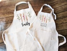 two personalized aprons sitting on top of a wooden table