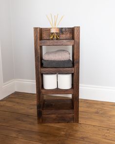 a wooden shelf with two rolls of toilet paper on it and some towels in the middle