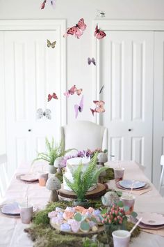 a table topped with lots of plates and cups next to a wall covered in butterflies