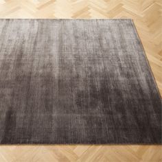 a large gray rug on top of a wooden floor with parquet floors in the background