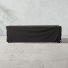 a table covered with a black cloth sitting on top of a floor next to a wall