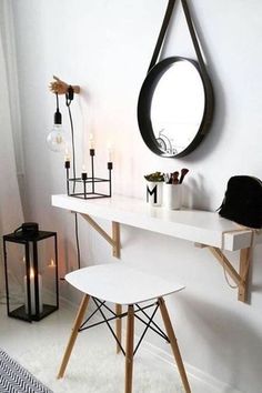 a white desk with two chairs and a round mirror on the wall above it in a room