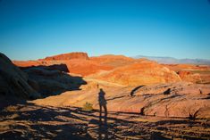 a person standing in the middle of a desert with mountains in the backgroud