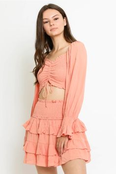 Adorable Peach Two Piece Set - Long Sleeve Crop Top - Ruffle Skirt | Bohopink Embrace the femininity of the Give Me Fever Peach Sunset Two-Piece Dress! Lightweight white fabric forms this two-piece dress set, with crop top and matching mini skirt. Off-the-shoulder long sleeve crop top with a ruched smocked bodice that ties at the waist. Matching ruffle tiered high-waisted smocked mini skirt. Pink Two-piece Set Top For Spring, Spring Two-piece Crop Top With Mini Length, Feminine Long Sleeve Crop Top For Brunch, Spring Two-piece Mini Crop Top, Flirty Long Sleeve Crop Top, Pink Ruched Crop Top For Spring, Long Sleeve Pink Crop Top For Summer, Long Sleeve Ruched Crop Top For Summer, Long Sleeve Ruffled Crop Top For Spring