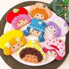 there are many cookies decorated to look like children's faces on a plate with leaves in the background