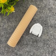 a pair of gloves sitting next to a roll of toilet paper on the ground with yellow flowers in the background