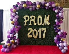 purple and gold balloon arch with prom date on it in front of a red carpet