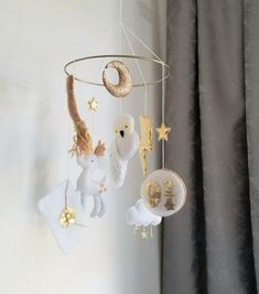 a baby mobile hanging from the ceiling next to a window with curtains and drapes