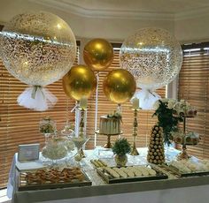 a table topped with lots of balloons filled with gold and white confetti balls