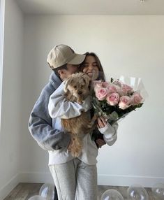 a man and woman holding a small dog in their arms with balloons floating around them