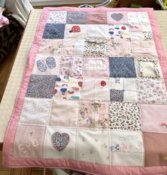 a pink and blue patchwork baby quilt on a table with a teddy bear next to it