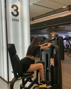 a woman is sitting on a machine in the gym