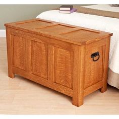 a wooden trunk sitting on top of a hard wood floor next to a white bed