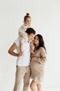 a man, woman and child are posing for a family photo in front of a white background