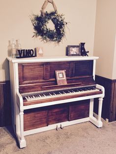 an old piano is in the corner of a room with a wreath on top of it