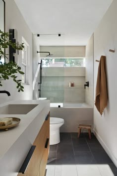 a bathroom with a toilet, sink and bathtub next to a plant in the corner