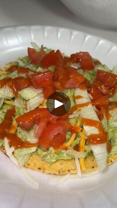 a white plate topped with an enchilada covered in lettuce and tomatoes