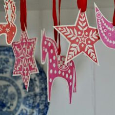 some ornaments are hanging from the ceiling with red and pink decorations on them in front of a blue plate