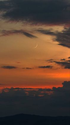 an airplane is flying in the sky at sunset or dawn with a crescent moon behind it