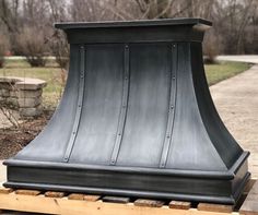 a black stove hood sitting on top of a wooden pallet