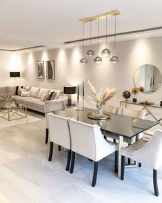 a living room filled with white furniture and lots of mirrors on the wall above it