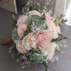 a bridal bouquet with pink roses and baby's breath flowers on a wooden floor