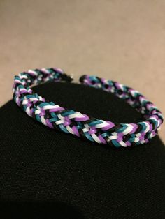 a purple and blue braided bracelet sitting on top of a black mannequin