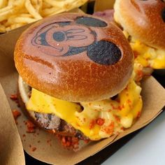 two mickey mouse burgers with cheese and fries on the side, ready to be eaten