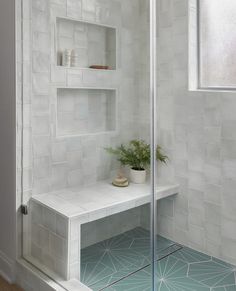 a white tiled bathroom with shelves and plants