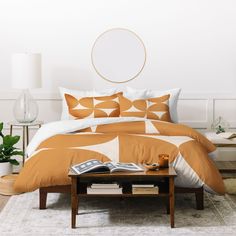 a bed with an orange and white comforter in a room next to a table