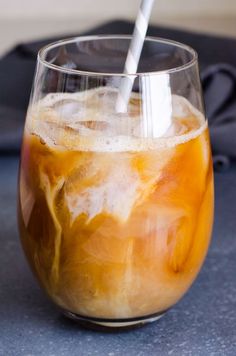 a glass filled with liquid and ice on top of a blue countertop next to a black bag