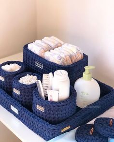 a blue basket filled with lots of items on top of a white counter next to slippers