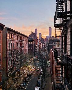 a city street filled with lots of traffic next to tall buildings and fire escape ladders