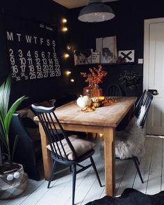 a dining room table with two chairs and a calendar on the wall