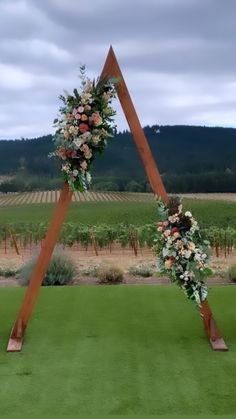 a wedding arch decorated with flowers and greenery in the middle of a vineyard field