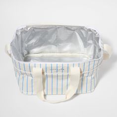 a blue and white striped tote bag sitting on top of a white tablecloth