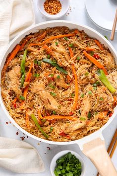 a white dish filled with chicken and veggies on top of a table next to chopsticks