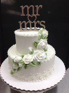 a wedding cake with white flowers and mr and mrs on top