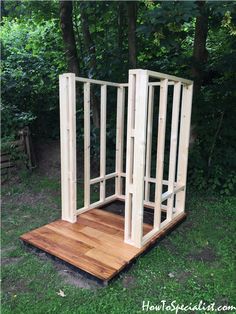 a wooden structure sitting on top of a lush green field with trees in the background