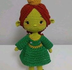 a crocheted doll with a red hair wearing a green dress and a yellow crown