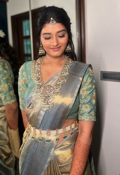 a woman in a sari is looking down at her hand on her hip while standing next to a mirror