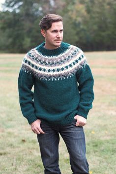 a man standing in the grass wearing a green sweater with fair - knitted details