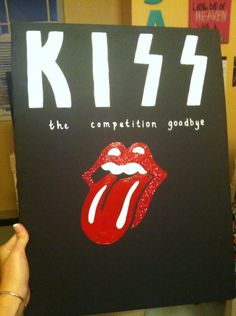 a person holding up a sign with the rolling stones on it that says kiss the competition goodbye