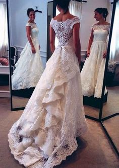 a woman standing in front of a mirror wearing a wedding dress with ruffles