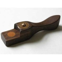 a wooden object with a metal button on the top of it's handle, sitting on a white surface